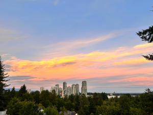 a city skyline under a cloudy sky at sunset at Sandy's Sweet Home in Coquitlam