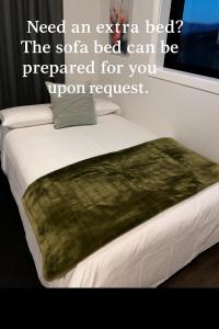 a bed with a green blanket on top of it at Queenstown Studio with Mountain Views in Frankton