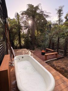 a bath tub sitting on top of a deck at Mamaku Hideaway - with outdoor bath in Greymouth