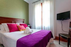 ein Schlafzimmer mit einem großen Bett mit einer lila Decke in der Unterkunft Hotel Baco in Sevilla
