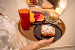 a person holding a tray of breakfast foods and drinks at Bali Bay by Urban Haven in Sanur