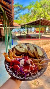 una persona sosteniendo un plato de comida en una mesa en Pousada e Restaurante Recanto Dos Gaviões, en Salvaterra