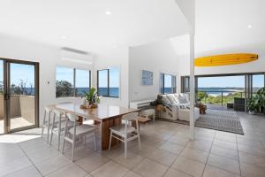 ウールグールガにあるZiggy's Beach House - Ocean views, Jacuzzi, Sauna!のテーブルと椅子のあるリビングルームとダイニングルーム