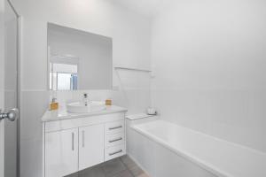 ウールグールガにあるZiggy's Beach House - Ocean views, Jacuzzi, Sauna!の洗面台と鏡のある白いバスルーム +17枚の写真