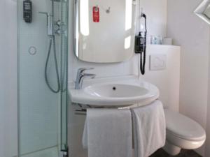 a bathroom with a sink and a toilet and a mirror at ibis Köln Centrum in Cologne