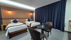 a hotel room with two beds and a table and chairs at The River khaosok in Khao Sok