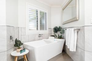 une salle de bain blanche avec une baignoire et une fenêtre dans l'établissement Spacious Coastal Oasis - Ideal for Groups & Families, 
