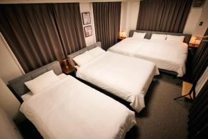 東京にあるとまりーとStay 西五反田の白いシーツが敷かれたホテルの部屋にベッドが2つある