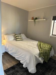 a small bedroom with a bed with white sheets at Chilltown Burrill Lake in Burrill Lake