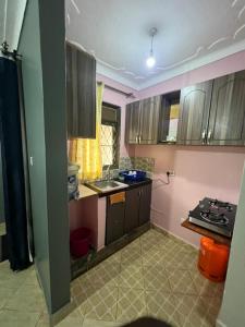 a kitchen with pink walls and wooden cabinets at Cozy suites 3 in Kampala