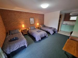 a room with two beds and a brick wall at 1st T Motel in Mirboo North
