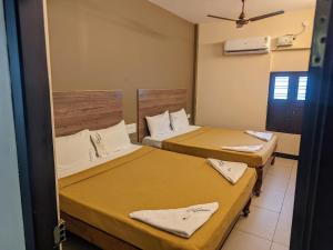 una habitación con dos camas y una ventana en Nathan's Residency, en Tiruchchirāppalli