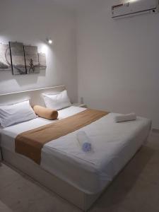 una camera da letto con un letto grande con lenzuola e cuscini bianchi di Theodore Hotel - Negombo a Negombo