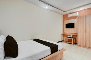 a hotel room with a bed and a television at Hotel O Kachohalli Gate Formerly SRS Lodge in Tāvarikere +23 photos