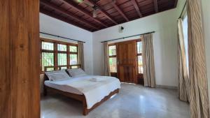 a bedroom with a bed in a room with windows at Thistle Cosy Villa in Kozhikode