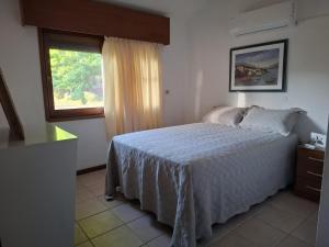 Un dormitorio con una cama blanca y una ventana. en Casa en Piriápolis para ocho personas grande y luminosa, en Piriápolis