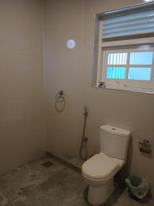 bagno con servizi igienici bianchi e finestra di Theodore Hotel - Negombo a Negombo