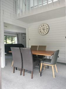 a dining room with a table and chairs and a clock at Hawkings Lodge in Kerikeri