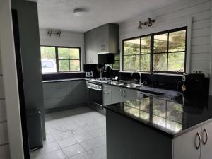 a large kitchen with black counter tops and windows at Hawkings Lodge in Kerikeri