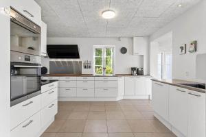 a white kitchen with white cabinets and a tv at FY285-Faaborg-Egsgyden-35 in Fåborg