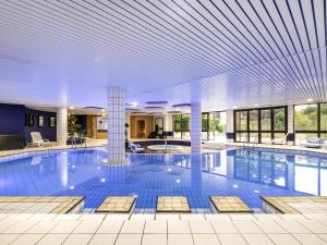 a large swimming pool in a building with a ceiling at Mercure Tours Sud in Joue-les-Tours
