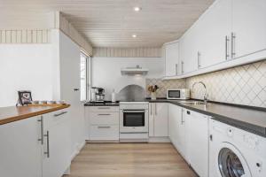 a kitchen with white cabinets and a washer and dryer at FY290-Faaborg-Egholmvej-14 in Faaborg