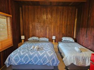 two beds in a room with wooden walls and wood at Kin Kin Retreat in Quinninup