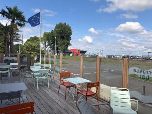 a deck with tables and chairs and a parking lot at ibis Styles Ouistreham in Ouistreham