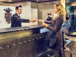 a man handing a woman a ticket at a counter at Mercure Villa Romanazzi Carducci Bari in Bari