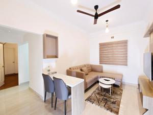 een woonkamer met een bank, een tafel en stoelen bij Proximus - Boutique Hotel Apartments in Bangalore