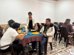 een groep mensen die rond een tafel zitten te eten bij River Era by Naavagat in Jibhi +61 foto's