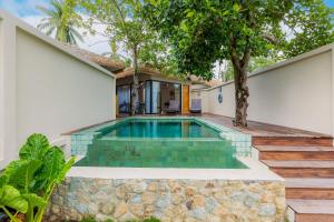 a swimming pool in the backyard of a house with a tree at Samaraya Wellness Resort - Adults Only in Lipa Noi +68 photos