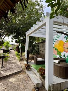 une pergola blanche avec un canapé et des chaises dans une cour dans l'établissement Le Jardin Arhumatic Sambava, à Sambava