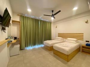 a hotel room with two beds and a television at Thila Sky View in Thoddoo
