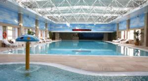 a large swimming pool with a umbrella in a building at Teda Dalian in Dalian
