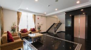 a living room with couches and a table and a staircase at Romance Hotel Srinakarin in Bangkok