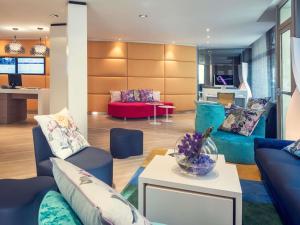 a living room with blue couches and a red couch at Mercure Nice Centre Grimaldi in Nice