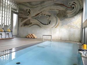 a swimming pool with a painting on the wall at Kakeyu Onsen Hotel Kameya in Ueda