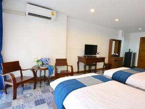 a hotel room with two beds and a desk and a television at The Indigo House Phrae in Ban Rong Fong