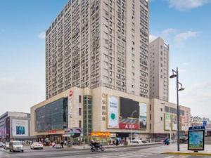 a large building on a city street with cars at Xana Hotelle Suqian Soho Ginza Branch in Suqian