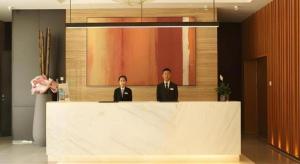two men are standing behind a counter in a lobby at Jinjiang Inn Select Xixian New Distict Century Avenue in Xianyang