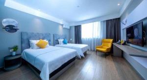 a hotel room with two beds and a yellow chair at Magnotel Chengdu Kuanzhai Alley Tongjin Bridge Hotel in Chengdu