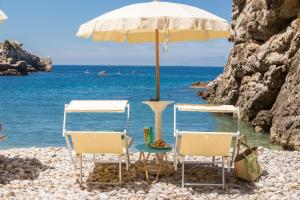 two chairs and an umbrella on the beach at Relais Regina Giovanna in Sorrento