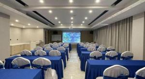 a room with blue tables and chairs and a screen at Echarm Hotel Yingshang High-speed Railway Station Wuzhou Wanhui Plaza in Jingzhuang