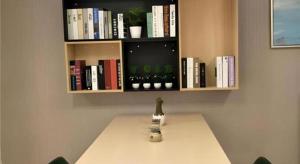 a table with a vase on a table with a book shelf at City Comfort Inn Jiangxia Wuchang University of Technology in Wuhan +22 photos
