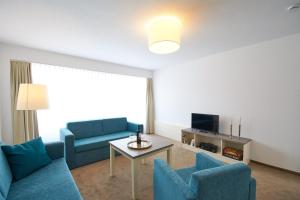 ein Wohnzimmer mit 2 blauen Stühlen und einem Tisch in der Unterkunft Nordsee Apartments in Bremerhaven