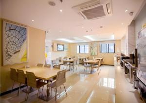宜昌市にあるCity Comfort Inn Yichang Dongshan Three Gorges University Shuiyuechengの木製のテーブルと椅子のあるダイニングルーム