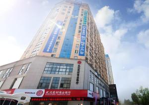 宜昌市にあるCity Comfort Inn Yichang Dongshan Three Gorges University Shuiyuechengの横に看板が多く建つ高層ビル