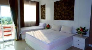a bedroom with two beds and a large window at Crystal Place Prathai in Prathai