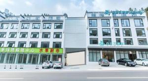 黄山風景区にあるMagnotel Hotel Huangshan Scenic Area Transfer Centerの大きな白い建物とその前に駐車された車